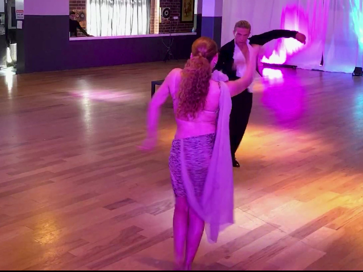 Blayne Allen dancing a ballroom hold with a partner under purple light